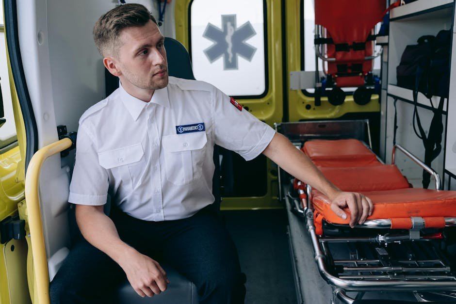 Paramedic Sitting at the Back of an Ambulance by the Gurneys